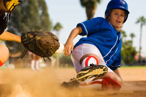 Softball player sliding into home plate