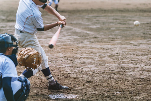 Baseball player swinging bat with catcher behind him.