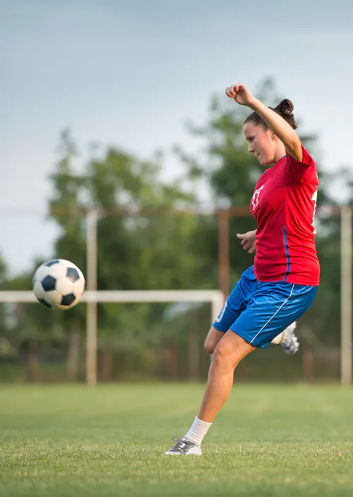 Female soccer player kicking the ball