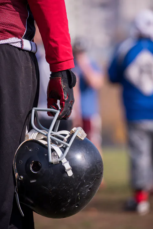 Football player holding black helmet.