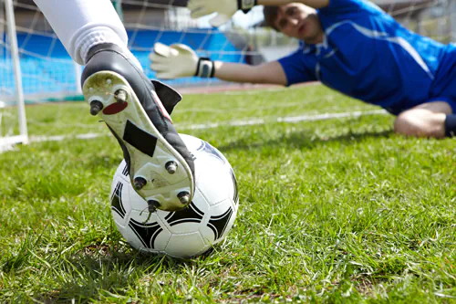 Soccer ball with foot of player kicking it into goal